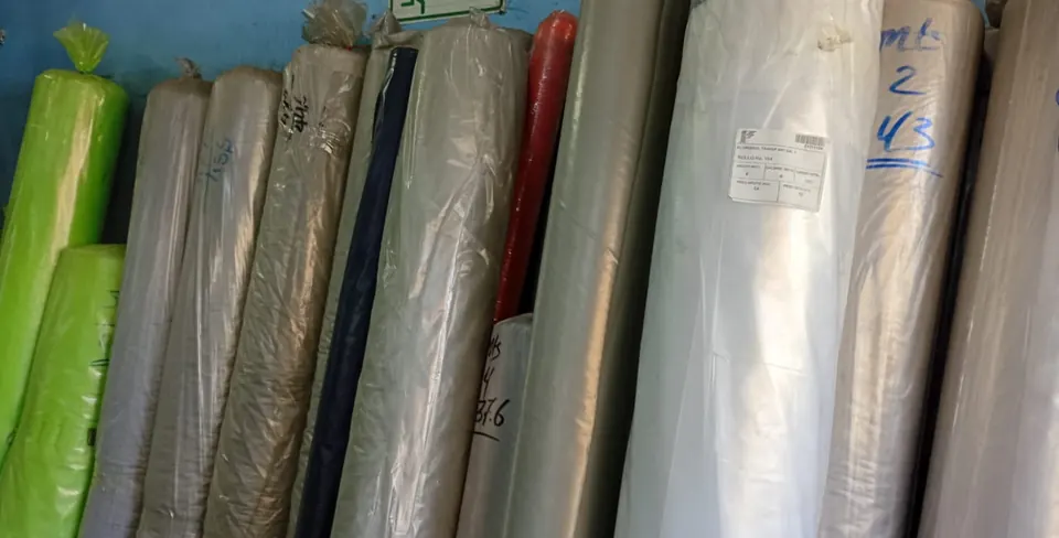 Rollos de plástico de varios colores y anchos, de pie en bodega.